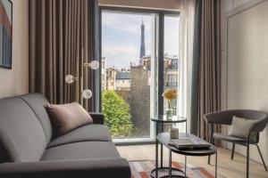 uma sala de estar com um sofá e uma grande janela em Canopy By Hilton Paris Trocadero em Paris