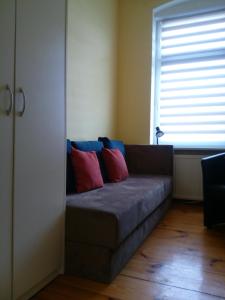 a couch with two pillows on it in a room at Hostel Tulip - pokój 6 ze wspólną łazienką i kuchnią in Szczecin