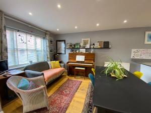 uma sala de estar com um sofá e um piano em Artist's eclectic Town House close to river em Woodbridge