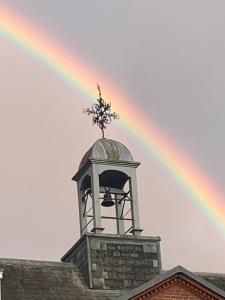 un arco iris sobre un edificio con una torre de reloj en The Courtyard, en Newmarket