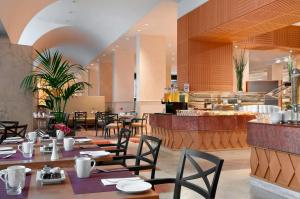 a restaurant with tables and chairs and a counter at Hilton Rome Airport in Fiumicino