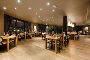 un ristorante con tavoli e sedie in legno e finestre di DoubleTree by Hilton Royal Parc Soestduinen a Soestduinen