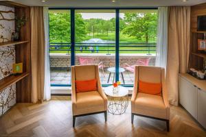 a room with two chairs and a table and a balcony at DoubleTree by Hilton Royal Parc Soestduinen in Amersfoort