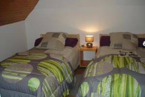 a bedroom with two beds and a table with a lamp at Les Gîtes Bleus de Lannion - avec cuisine- in Lannion