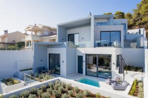 ein großes weißes Haus mit einem Pool in der Unterkunft White Cliff Luxury Suites by A&D Properties in Porto Rafti
