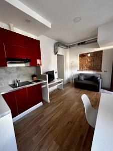 cocina y sala de estar con armarios rojos y sofá en Apartment Lake Varese - Lago di Varese -, en Lomnago