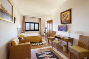 um quarto de hotel com uma cama, uma secretária e cadeiras em Hotel Baglio Santacroce em Valderice
