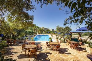 un patio con tavoli, sedie e piscina di Hotel Baglio Santacroce a Valderice
