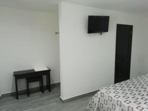 1 dormitorio con cama, mesa y TV en HOTEL QUINTERO, en Teapa