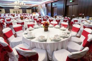 un salón de banquetes con mesas blancas y sillas rojas en Hilton Garden Inn Astana en Astaná