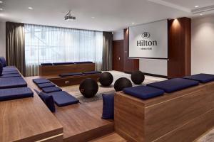 een vergaderzaal met blauwe stoelen en een projectiescherm bij Hilton Vienna Park in Wenen