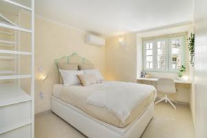 a white bedroom with a bed and a desk at Gardenland House Leiria in Leiria