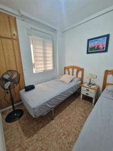 - une chambre avec 2 lits, un ventilateur et une fenêtre dans l'établissement Casa Margarita, à Torrevieja