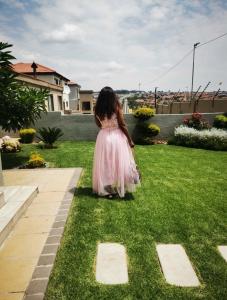 a woman in a pink dress walking on the grass at Sagewood Manor in Midrand