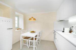 una cucina bianca con tavolo e frigorifero bianco di Gardenland House Leiria a Leiria