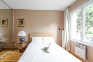 a bedroom with a large white bed with a window at Lovely house with garden Saint-Cloud near Paris - Welkeys in Saint-Cloud