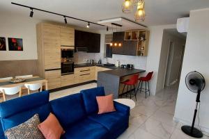 a living room with a blue couch and a kitchen at 2-bed apartment in Mellieha in Mellieħa