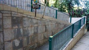 a stone retaining wall with a green fence at Pousada dos Ventos São Lourenço in São Lourenço