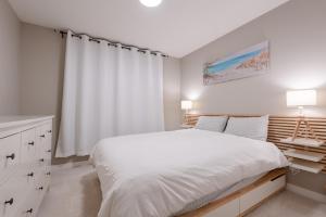 biała sypialnia z dużym łóżkiem i oknem w obiekcie Modern 3 Bedroom Home & Office & Media Room w mieście Cochrane