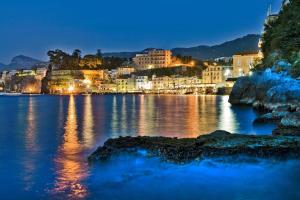a large body of water with a city at night at Hilton Sorrento Palace in Sorrento