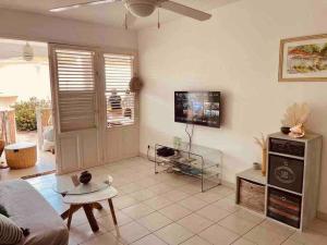 a living room with a couch and a tv at Sous les Tropiques…Vue mer in Les Trois-Îlets