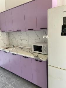 a kitchen with purple cabinets and a white refrigerator at Tastaq hostel in Almaty