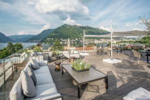 d'une terrasse avec canapés et tables et vue sur l'eau. dans l'établissement Hilton Lake Como, à Côme