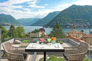 a table with wine glasses on a balcony with mountains at Hilton Lake Como in Como