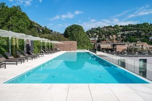 a pool on the roof of a building with chairs and umbrellas at Hilton Lake Como in Como