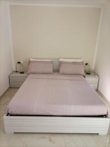 Cama blanca en habitación blanca con 2 lámparas en B & B CANTARANO, en Porto Garibaldi