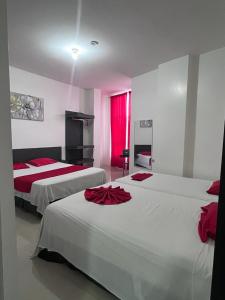 a hotel room with two beds with red sheets at HOTEL AMASH Chone in San Pablo