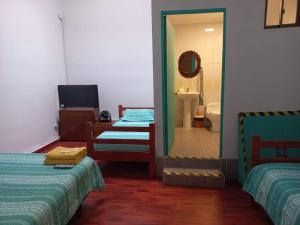 a room with two beds and a bathroom with a mirror at HOSTAL BAQUEDANO IQUIQUE in Iquique