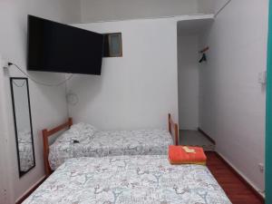a bedroom with two beds and a flat screen tv at HOSTAL BAQUEDANO IQUIQUE in Iquique