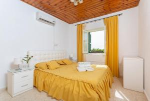 ein Schlafzimmer mit einem Bett mit gelber Bettwäsche und einem Fenster in der Unterkunft Androula Villas Collection in Kato Yialia
