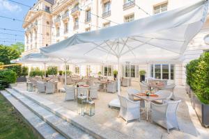 a restaurant with white umbrellas and tables and chairs at Waldorf Astoria Versailles - Trianon Palace in Versailles