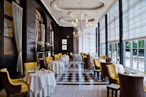 a restaurant with tables and chairs and a chandelier at Waldorf Astoria Versailles - Trianon Palace in Versailles