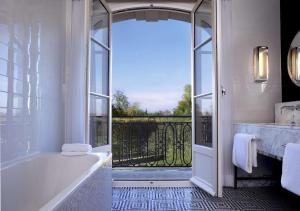 uma casa de banho com banheira e uma grande janela em Waldorf Astoria Versailles - Trianon Palace em Versailles