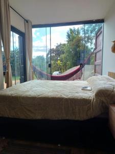 una camera con letto e finestra con amaca di Casa Container, Vista para o Lago e integrada com a Natureza - Miguel Pereira a Miguel Pereira