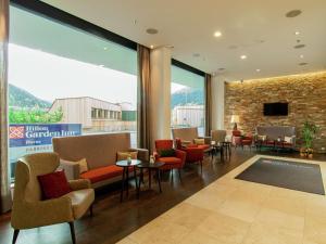 - un hall avec des chaises, des tables et une grande fenêtre dans l'établissement Hilton Garden Inn Davos, à Davos