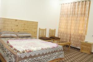een slaapkamer met een bed en een tafel en stoelen bij Ghizer Inn Hotel And Resturant in Gākuch
