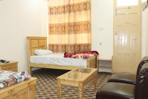 Zimmer mit 2 Betten, einem Stuhl und einem Tisch in der Unterkunft Ghizer Inn Hotel And Resturant in Gākuch