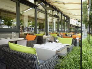 un restaurante con mesas y sillas blancas y ventanas en Hilton Antwerp Old Town, en Amberes