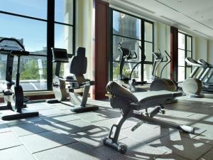 a gym with cardio equipment in a building with windows at Hilton Antwerp Old Town in Antwerp