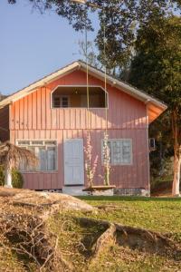 een rood huis met een witte deur in een tuin bij Gasthaus Heimat in Rio Forcação