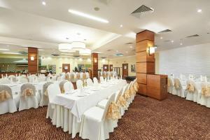 um grande salão de banquetes com mesas e cadeiras brancas em Hilton Garden Inn Krasnoyarsk em Krasnoyarsk