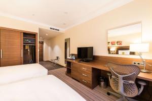 ein Hotelzimmer mit einem Bett und einem Schreibtisch mit einem TV in der Unterkunft Hilton Garden Inn Krasnoyarsk in Krasnojarsk