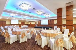 um salão de banquetes com mesas e cadeiras brancas e lustres em Hilton Garden Inn Krasnoyarsk em Krasnoyarsk