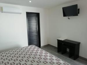 a bedroom with a bed and a flat screen tv at HOTEL QUINTERO in Teapa