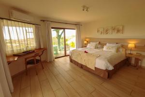 Schlafzimmer mit einem Bett, einem Schreibtisch und einem Fenster in der Unterkunft Hotel Hare Uta in Hanga Roa