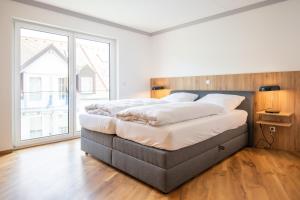 ein großes Bett in einem Zimmer mit einem großen Fenster in der Unterkunft Moderne Ferienwohnung direkt am Wasser in Heiligenstadt